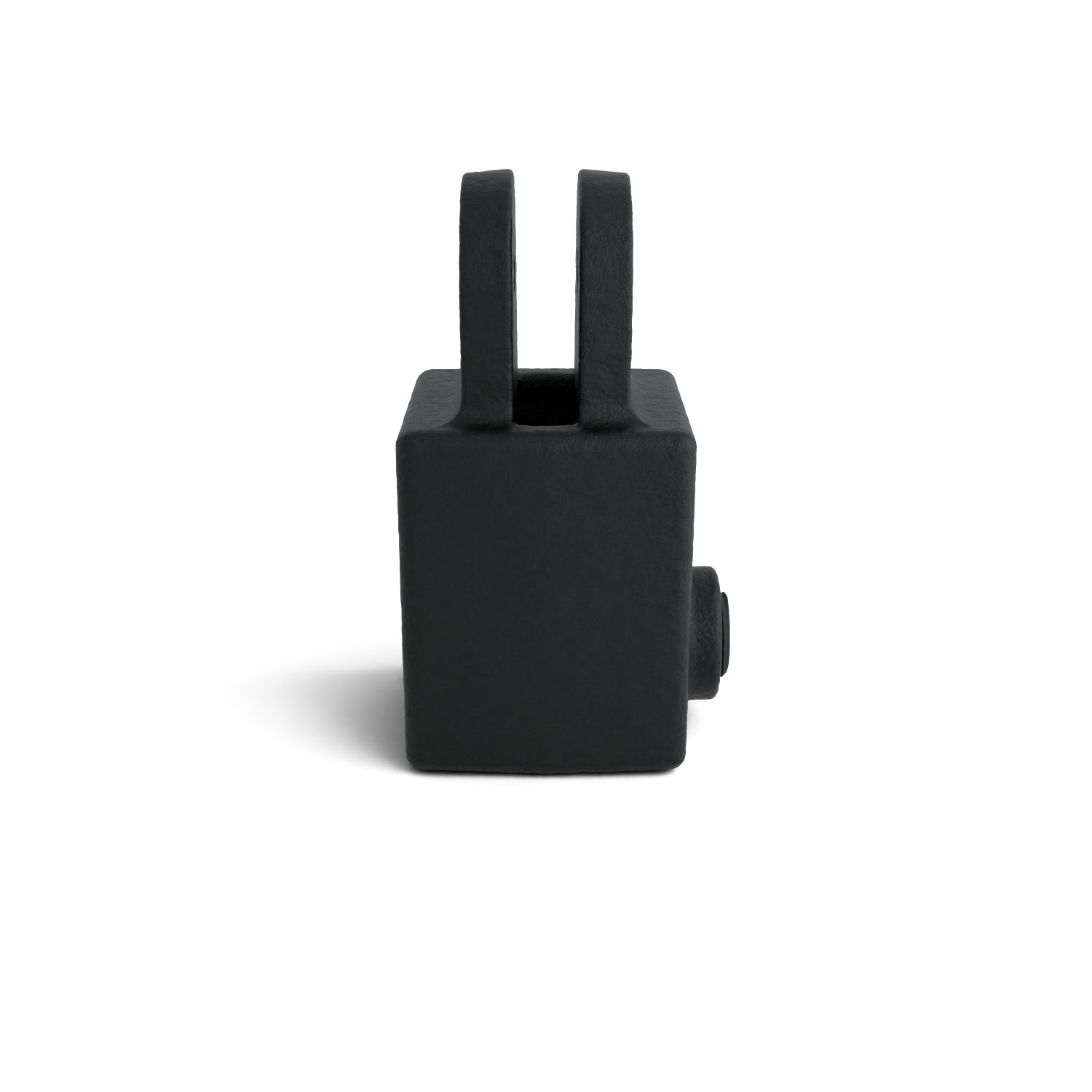 Un objeto rectangular de color negro mate se alza sobre un fondo blanco. En la parte superior sobresalen dos lengüetas paralelas en forma de U. A la derecha hay un pequeño saliente cilíndrico. Textura rugosa, sombra en la parte inferior izquierda.